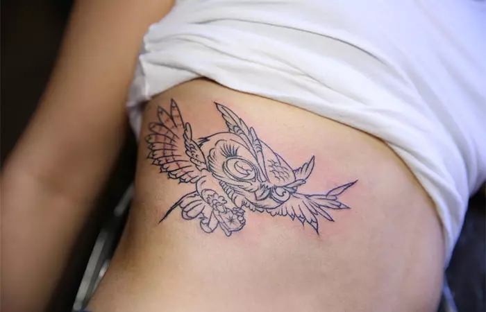 A woman with a 4x4 owl tattoo on the side of her body