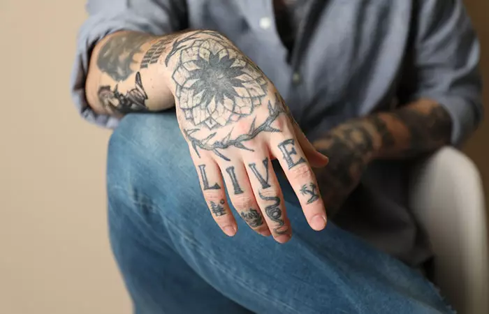 Close-up of a man with blackwork tattoos on his arm and fingers