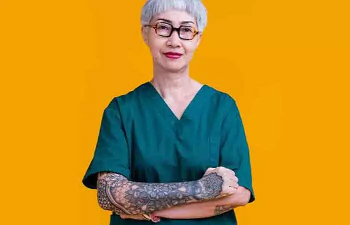 A senior doctor in scrubs sporting arm sleeve tattoos