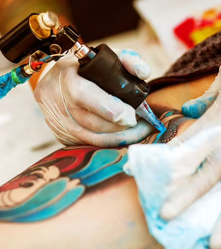 A tattoo artist covers up a black tattoo with colored ink