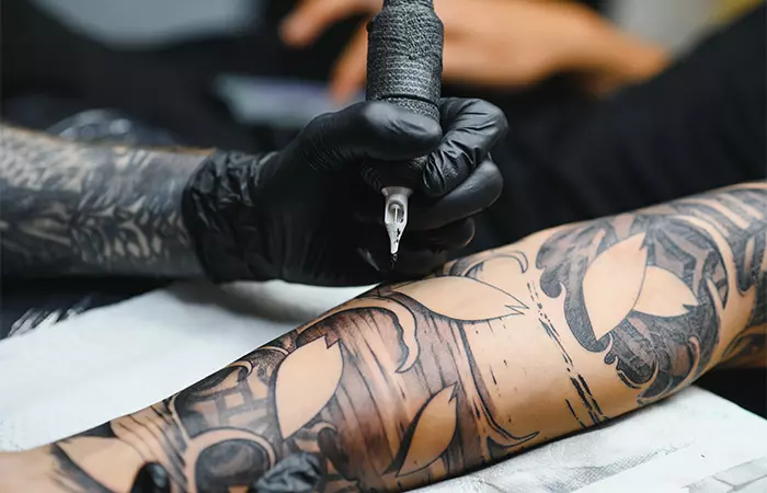 Close-up of a tattoo artist working on the client’s arm