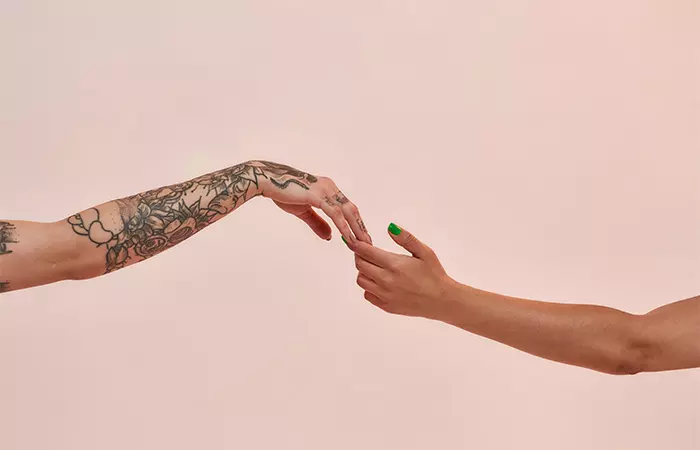 Close-up of a tattooed hand reaching out for a non-tattooed hand