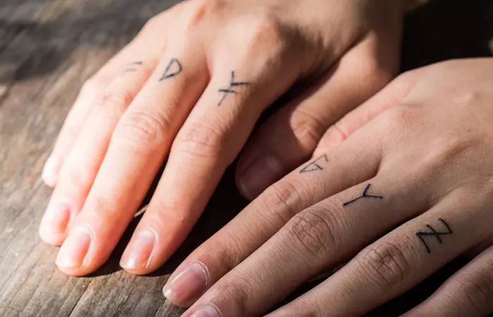 Hands with finger tattoos under sunlight