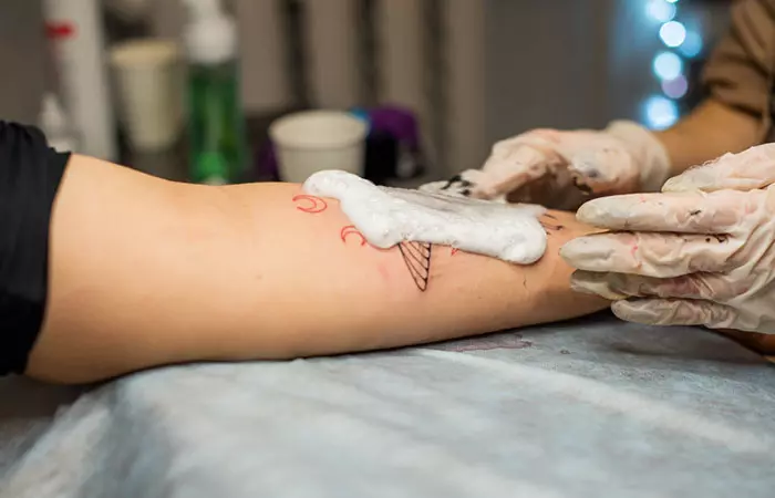 Tattoo artist cleaning a fresh glow-in-the-dark tattoo with foam