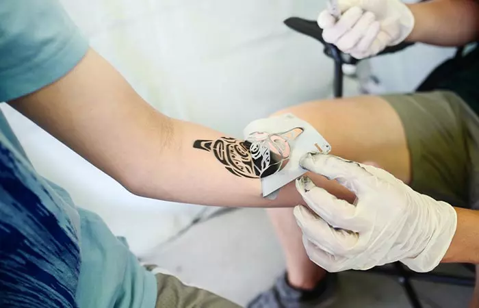 A tattoo artist fixing up a temporary tattoo.