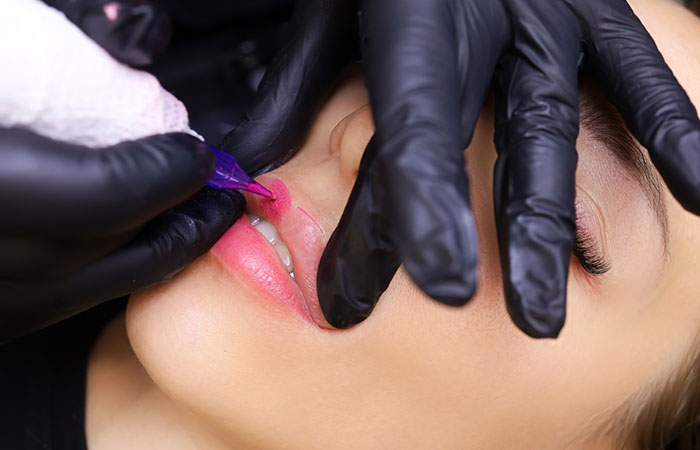 Tattoo artist performing a lip blushing procedure