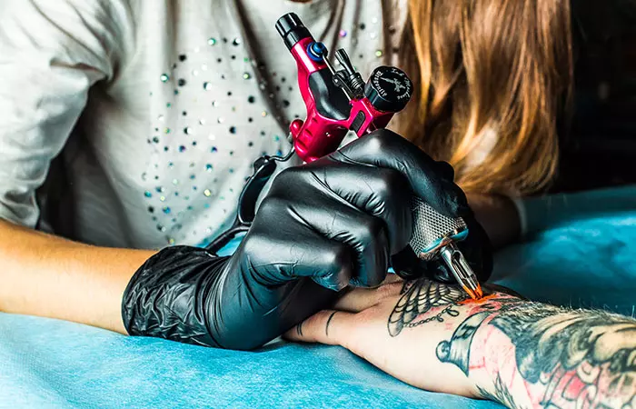 Tattoo artist working on a client’s hand