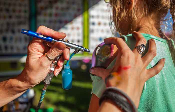 A child getting a temporary tattoo airbrushed by a professional tattoo artist.