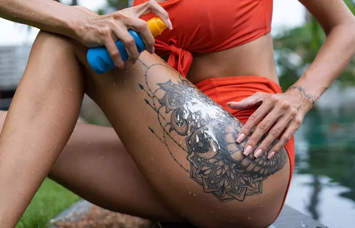 woman applying sunscreen on tattoo