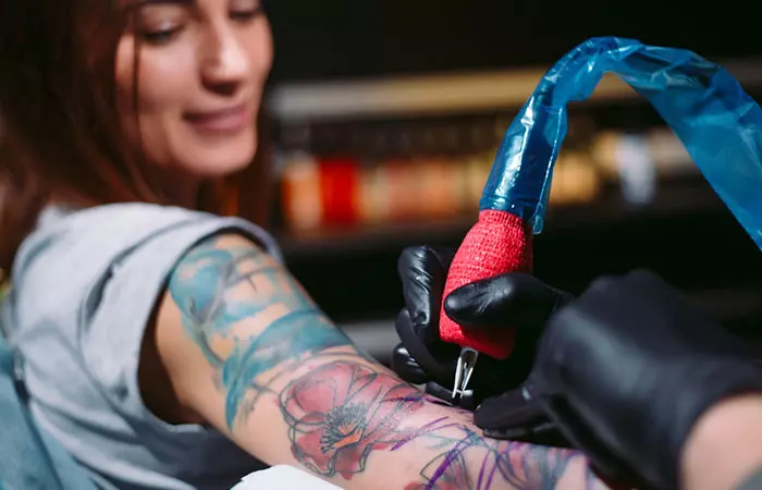 An artist tattooing a watercolor design on a woman
