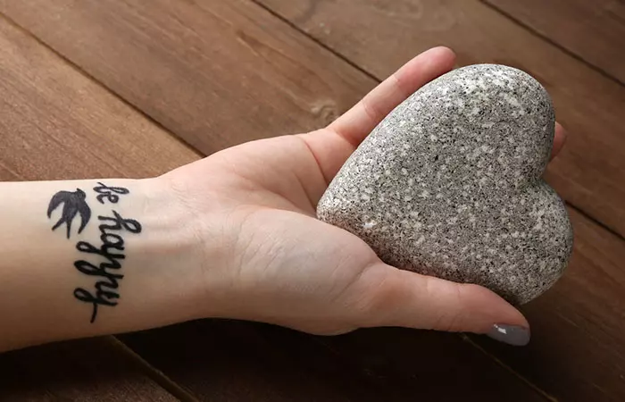 A woman with a flash tattoo on her inner wrist holding a stone