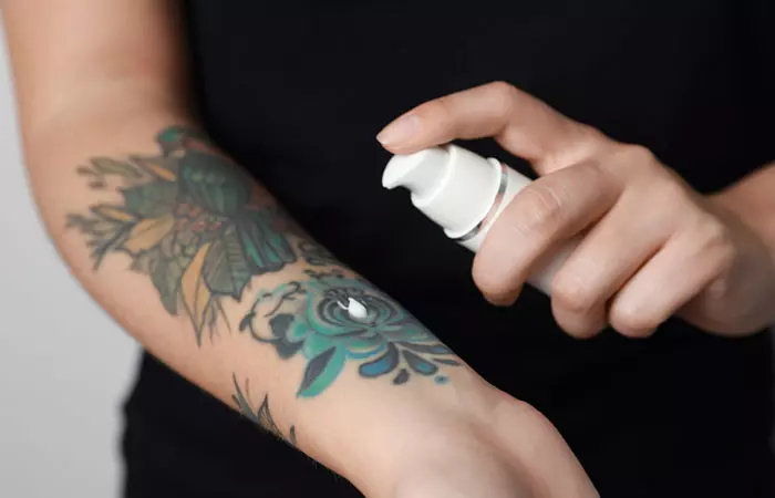 Woman applying lotion on her tattoo