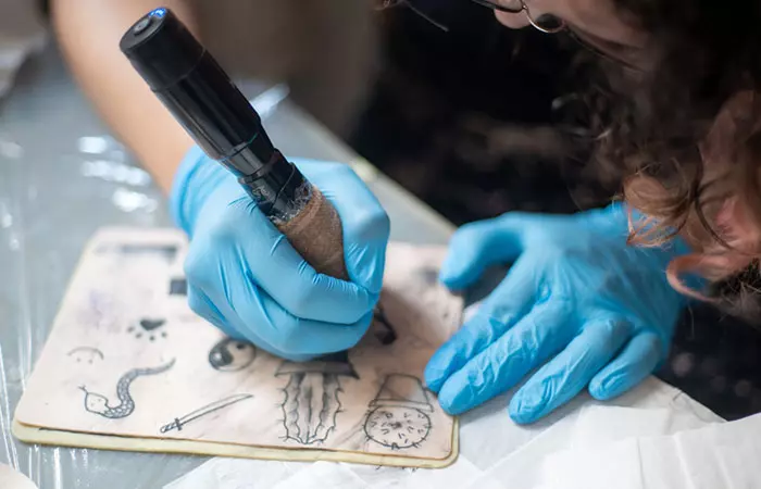 A tattoo artist working on a glow-in-the-dark tattoo design