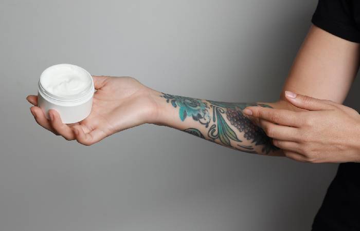 Woman applying moisturizer on a colored tattoo