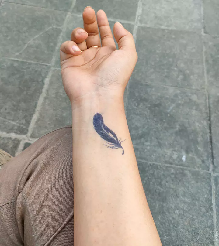 Woman with a black feather tattoo on her wrist