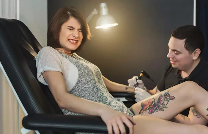 woman experiencing pain while tattooing