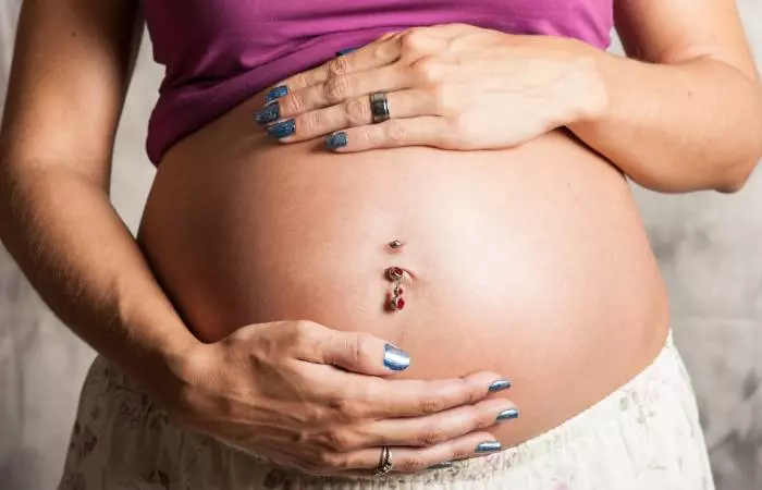 A pregnant woman with a belly button piercing