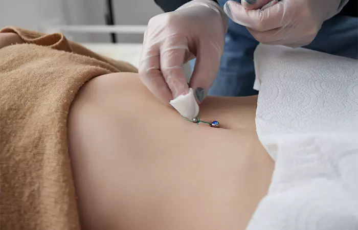 A belly button piercing being cleaned in sterile conditions