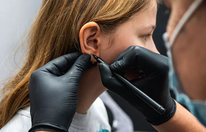A girl getting ready to get her ears pierced by a specialist