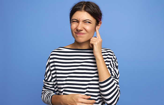 A girl in pain holding her ear due to piercing rejection