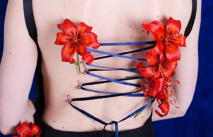 A girl with a back corset piercing decorated with lilies