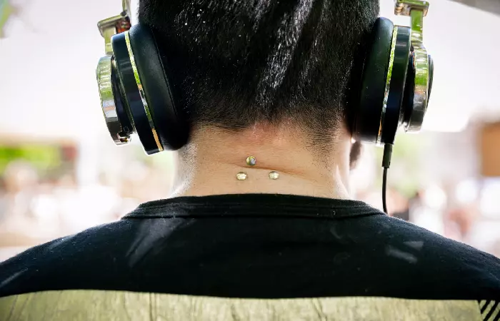 A man with three nape piercings.