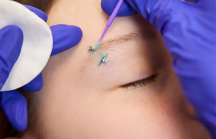 A person getting an eyebrow piercing