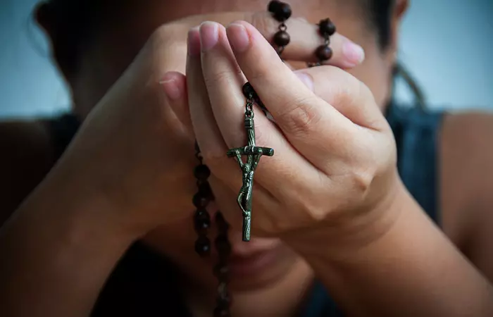 A person praying with a rosary