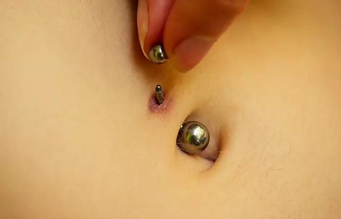 A person screwing on one end of their surface piercing
