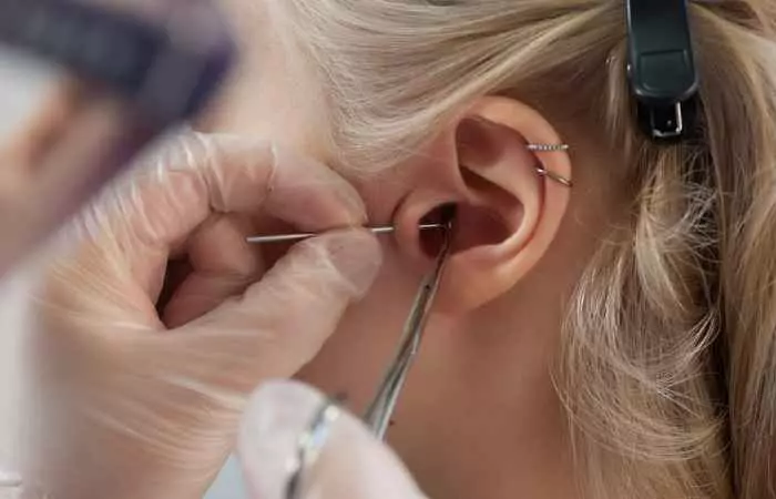 A professional doing a standard tragus piercing