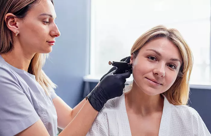 A professional piercer re piercing a closed ear piercing