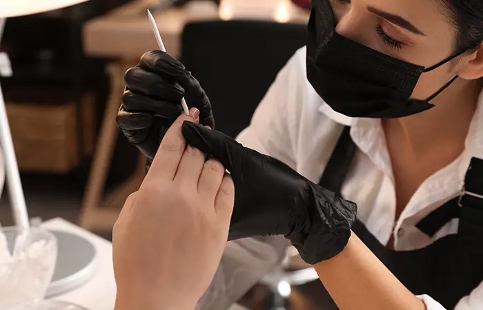 A professional preparing a client’s nails for nail piercing