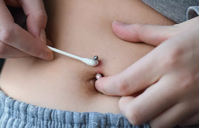 A woman caring for her belly piercing