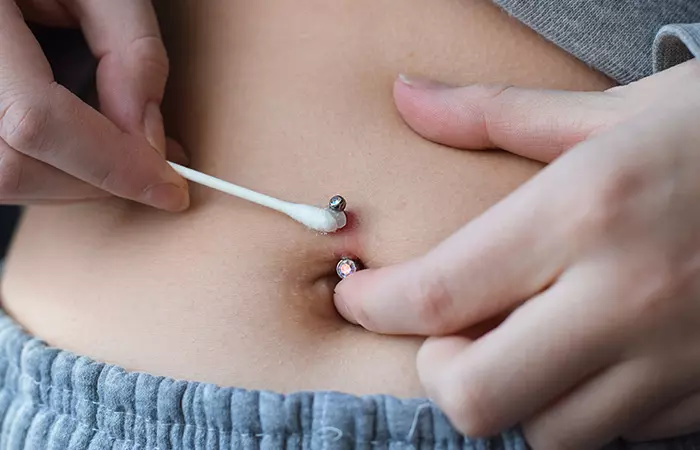 A woman cleaning her belly button piercing