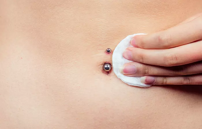 A woman cleaning her belly piercing