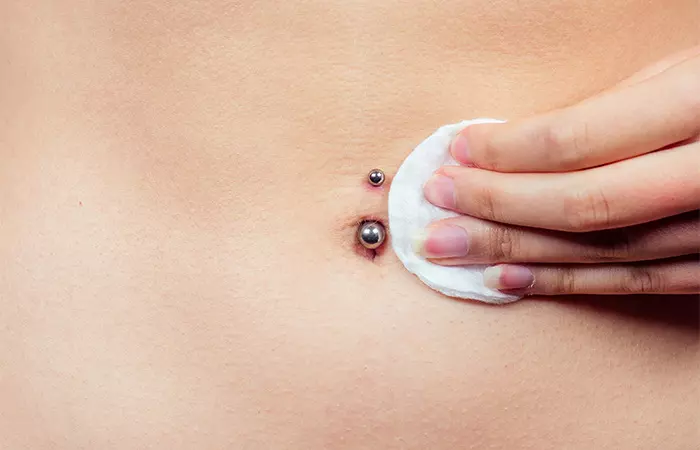 A woman cleaning her infected belly button piercing