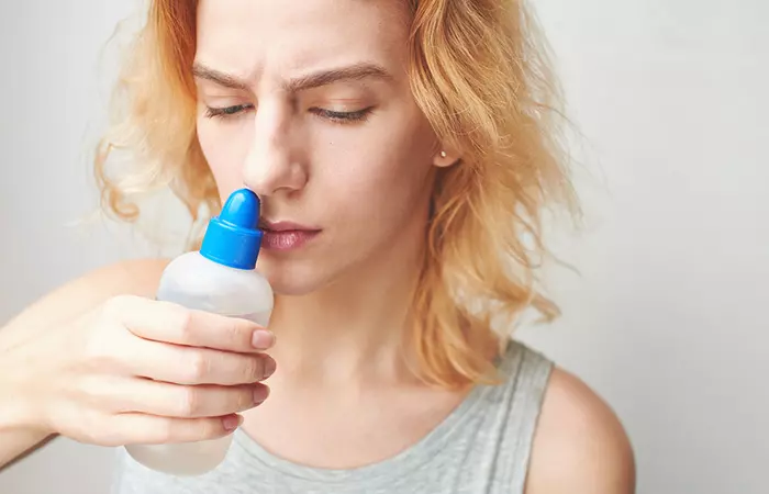 A woman cleaning her nose piercing with saline solution