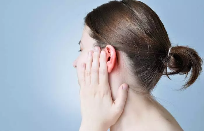 A woman experiencing pain from an infected ear piercing