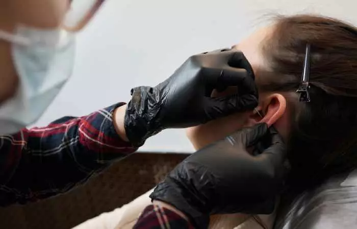 A woman getting a daith piercing for migraine