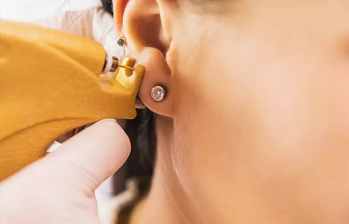 A woman getting a high lobe piercing