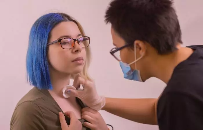 A woman getting her dermal piercing removed by a professional piercer