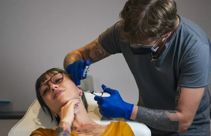 A woman getting her ear pierced by an experienced piercer