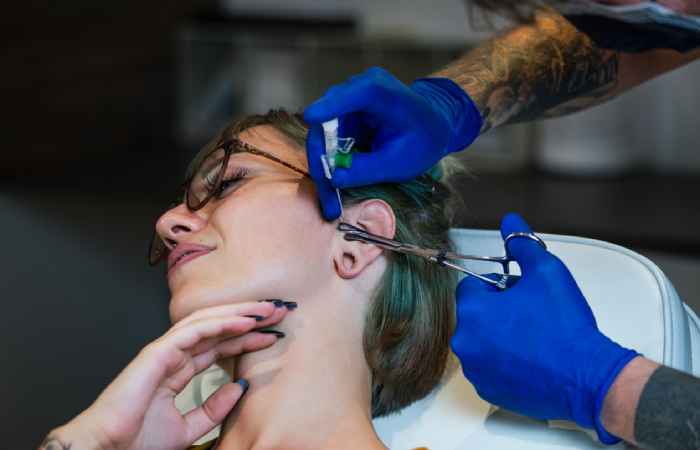 A woman getting her tragus pierced