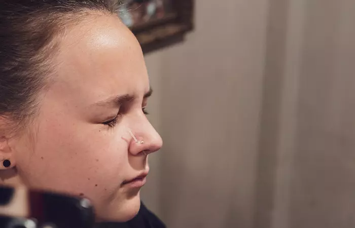 A woman in pain getting her nostril pierced