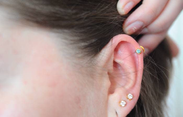 A woman sports a helix piercing