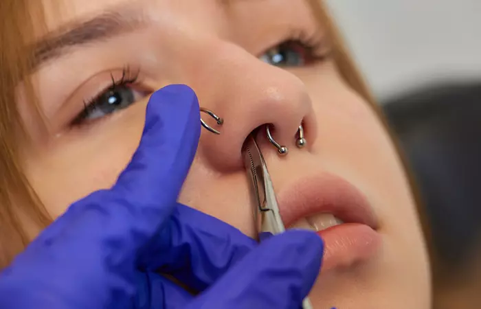 A woman undergoing a double nose piercing procedure