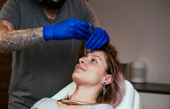 A woman undergoing a nose piercing procedure