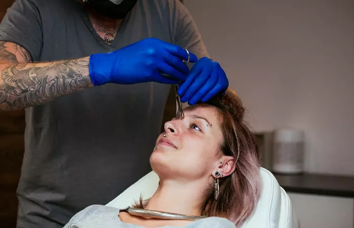 A woman undergoing a nose piercing procedure