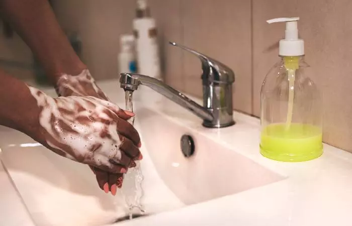 A woman washes her hands before cleaning her new piercing