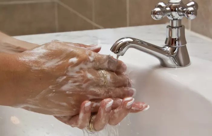 A woman washing her hands before touching her cartilage piercing bump
